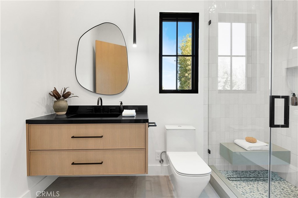 Custom bathroom vanity with black countertop and glass shower by Hillstar Construction in Los Angeles